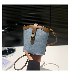 Close-up of contrast color bucket bag with turn-lock clasp and blue denim fabric detail