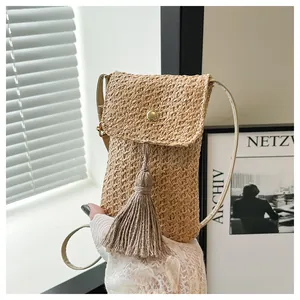 Detail of light brown woven crossbody bag featuring a metal snap closure and large tassel