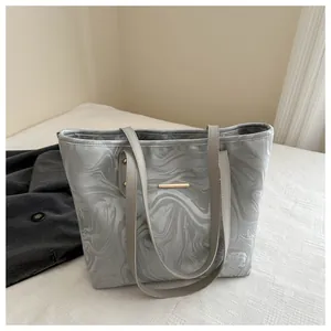 Detail of grey marble textured tote bag with gold metal strip and slim shoulder straps