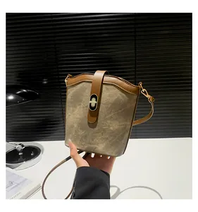 Close-up of retro canvas bucket bag with leather trim and golden metal turn-lock detail