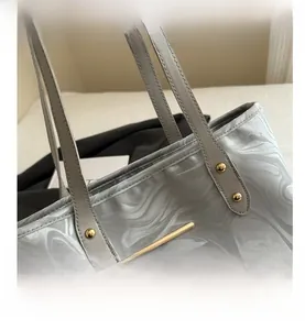 Detail showing marble pattern tote with grey leather strap and gold metal rivets