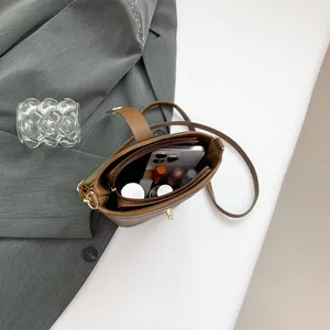 Brown leather bucket bag with gold turn-lock, showing spacious interior and compartments