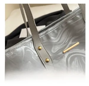 Detail of marble pattern tote bag with gold metal trim and reinforced stitching