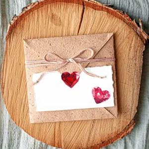 Gemas rojas románticas en forma de corazón con sobres de kraft y tarjeta de regalo blanca