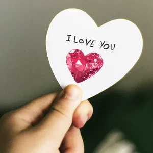 Primer plano de una gema rosa en forma de corazón sobre una tarjeta de amor romántica