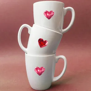Detalle de tazas de cerámica blanca apiladas con diseños de corazones de rubí y asas
