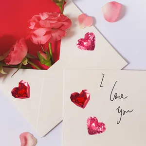 Vista plana de piedras preciosas en forma de corazón con rosas y un sobre de regalo