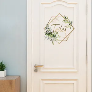 Detailed view of a geometric gold Toilet door sticker with green leaves on a white door