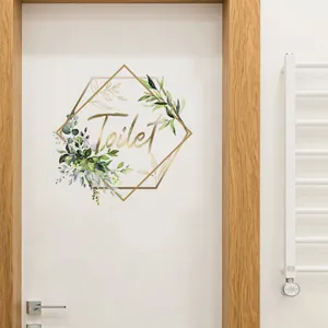 Detail of self-adhesive gold Toilet wall sticker with green leaves on white door