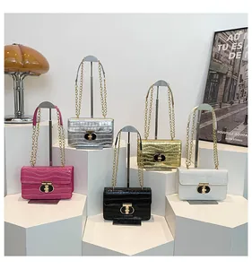 Detail of five croc-embossed chain bags on white geometric stands with metal ring locks