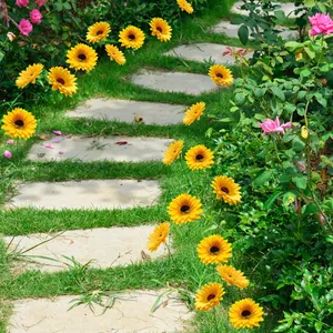 Vibrant sunflower garden stakes lining a stone pathway on a lush green lawn landscape