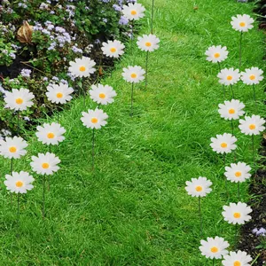 Detail showing white daisy garden stakes with metal rods arranged along a green grass path