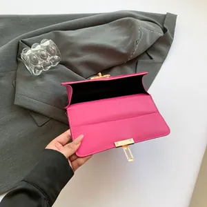 Hot pink chain bag with gold lock and black interior shown on a grey blazer garment