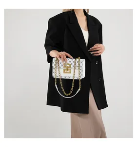 Détail d'un sac à main blanc avec motifs noirs et bandoulière en chaîne dorée