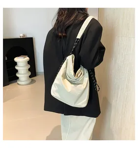 Detail of beige tote bag featuring textured fabric and black and white woven rope strap