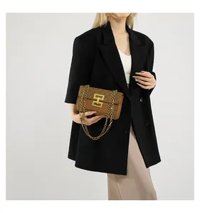 Sac bandoulière vintage marron avec boucle dorée et bandoulière chaîne porté par un modèle