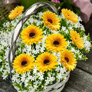 Artificial sunflower arrangement in a white woven basket on a dark wood floor