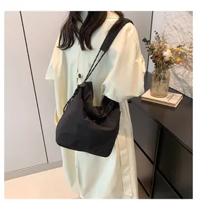 Detail of black nylon crossbody bag featuring textured fabric and drawstring shoulder strap