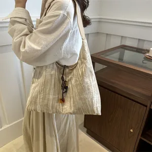 Minimalist beige tote bag with natural texture and amber decorative drawstring charm