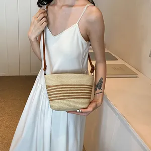 Straw woven striped bucket crossbody bag for women with brown leather shoulder strap
