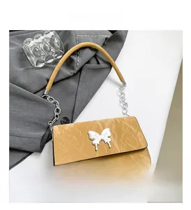 Detail of mustard yellow pleated handbag with silver butterfly clasp and chain strap
