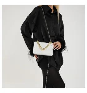 Detalle de bolso bandolera acolchado blanco con elegantes cadenas doradas y herrajes