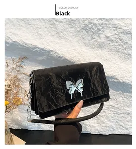Detail of black pleated shoulder bag featuring a silver liquid metal bow and chain