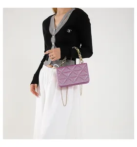 Detalle de bolso cuadrado rosa brillante de acrílico con cadena dorada y costuras triángulo