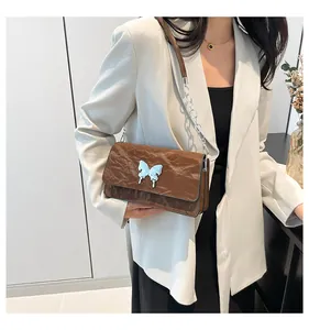 Close-up of brown textured leather shoulder bag with light blue butterfly buckle detail