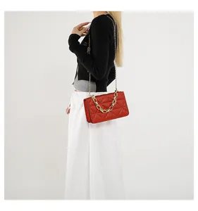 Detalle de bolso bandolera rojo acolchado en acrílico con cadena dorada en una modelo