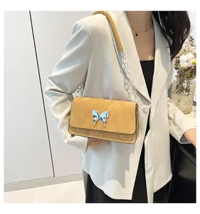 Close-up of yellow leather flap bag with silver liquid butterfly buckle and chain strap