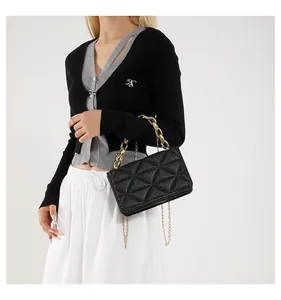 Detalle de bolso bandolera acolchado negro de acrílico con cadena de metal dorado