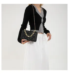 Detalle de bolso bandolera de acrílico negro acolchado con cadena dorada en modelo