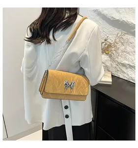 Detail of yellow baguette bag with silver butterfly buckle and chain strap on white blazer