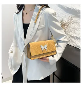 Close-up of yellow pleated shoulder bag with silver butterfly buckle and chain strap