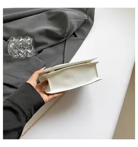 Primer plano del bolso de acrílico blanco perlado con detalles de cadena de metal dorado