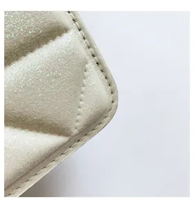 Primer plano del bolso marfil acolchado con acabado perlado y costuras de precisión