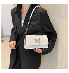 Detail of white shoulder bag with silver butterfly clasp and chain strap on a black blazer