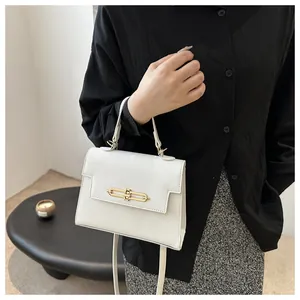 Détail du grain de litchi blanc et de la boucle en métal doré sur ce sac à bandoulière