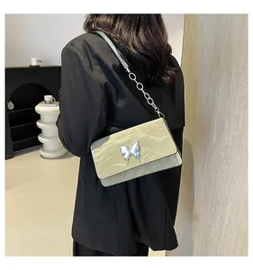 Detail view of light green pleated leather shoulder bag with a silver metal bow buckle