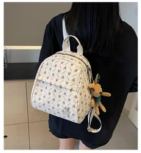 Detail of cream backpack featuring all-over rabbit logo print and plush bunny charm