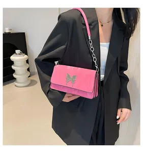Close-up of bright pink shoulder bag featuring a silver liquid-style metal butterfly detail