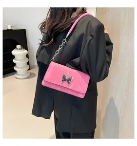 Detail of glossy pink wrinkled patent leather bag with a butterfly metal buckle