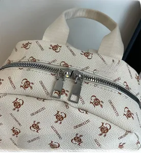 Detail of silver dual zippers and brown rabbit prints on a cream faux leather backpack