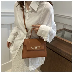 Détail du sac à main marron en cuir PU avec boucle dorée porté par un mannequin