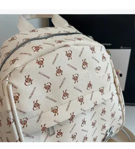 Close-up of off-white PU leather backpack featuring brown rabbit prints and metal zipper detail