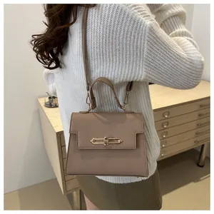 Sac bandoulière en PU marron à texture litchi porté par un mannequin en intérieur