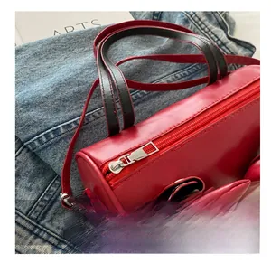 Detail view of the silver smooth zipper and bow design on the red cylinder bag