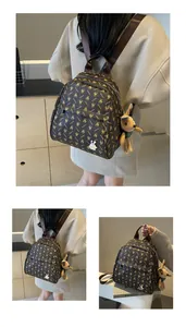 Close-up of brown monogram faux leather backpack with detachable plush rabbit keychain charm