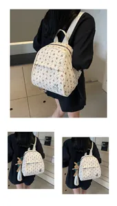 Detail view of cream backpack with brown rabbit prints and plush bunny charm on a model